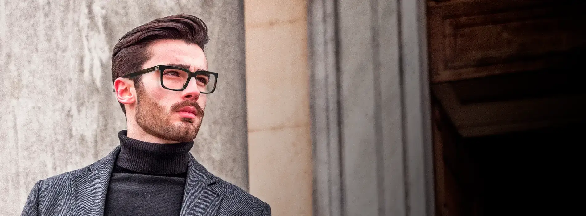 Hombre elegante con armazones Banderas Eyewear frente a columnas de piedra