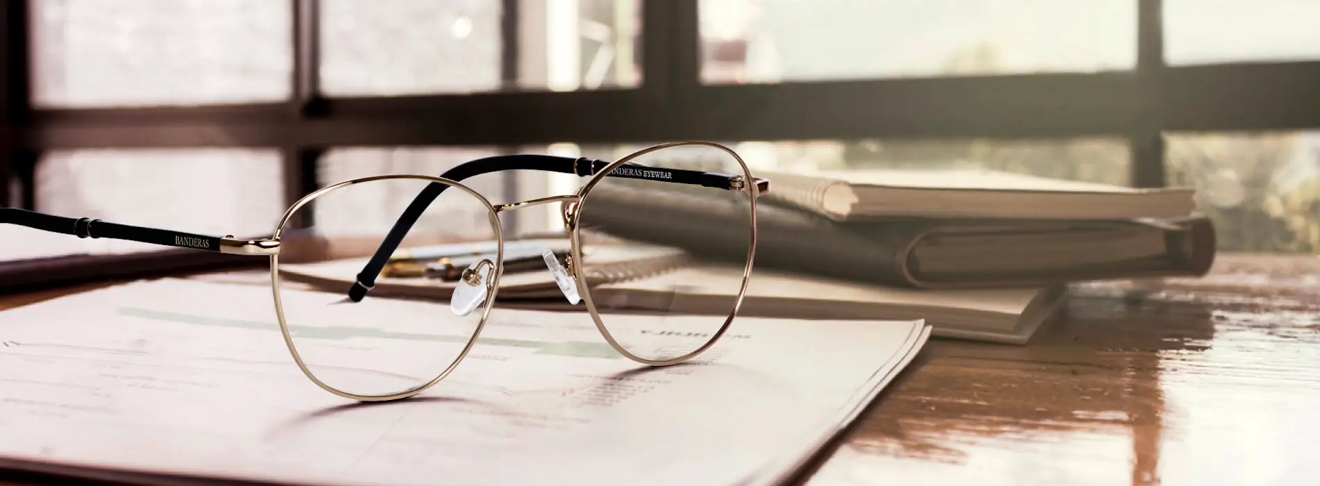Armazones dorados Banderas Eyewear sobre escritorio de madera